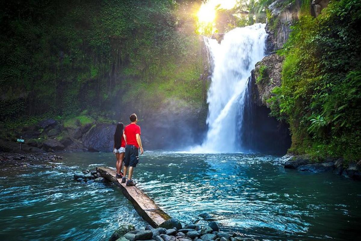 duas pessoas em pé em uma ponte em frente a uma cachoeira