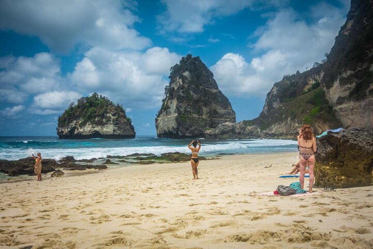 skupina ljudi, ki stojijo na plaži s skalnimi formacijami