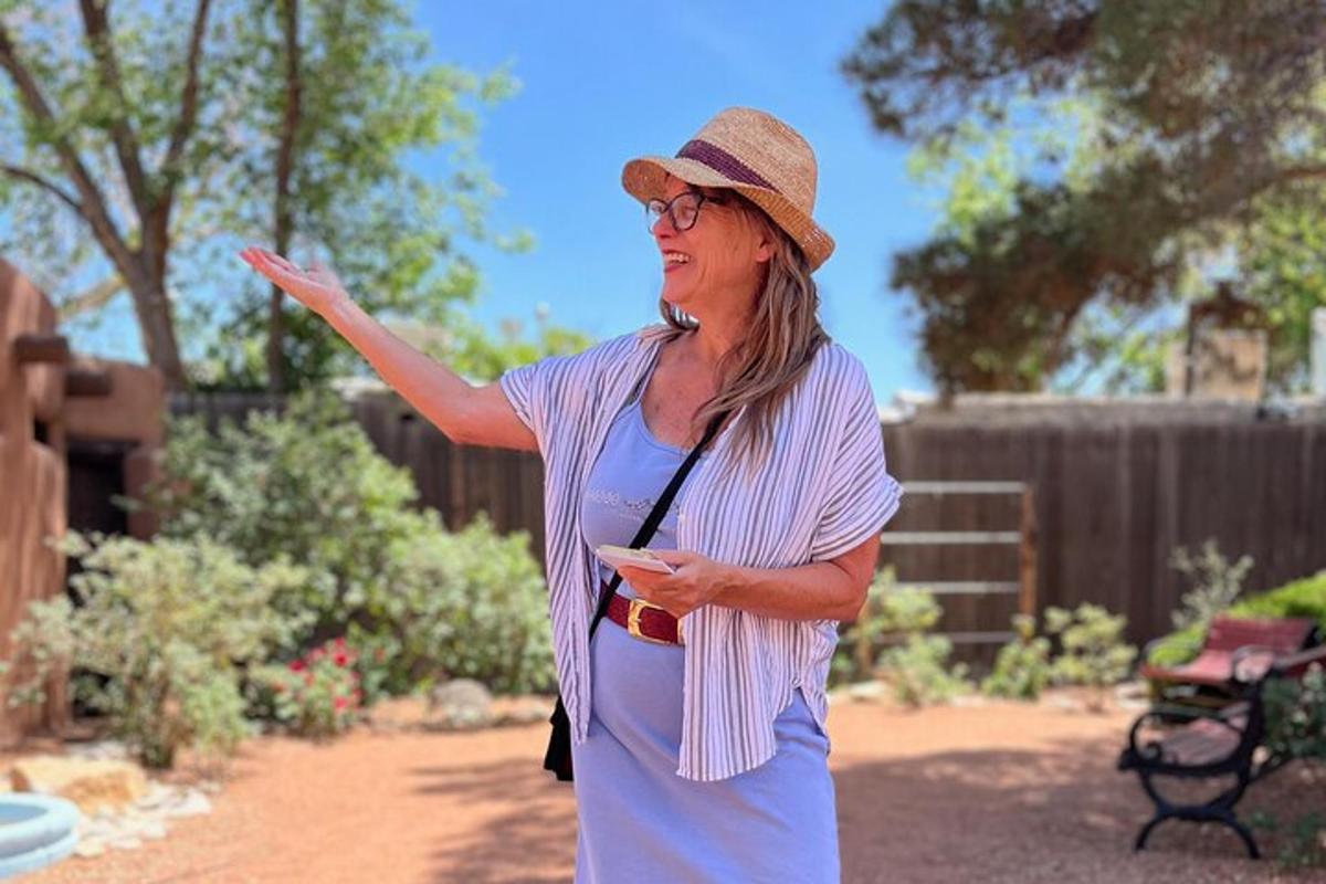 a woman wearing a hat standing in a garden