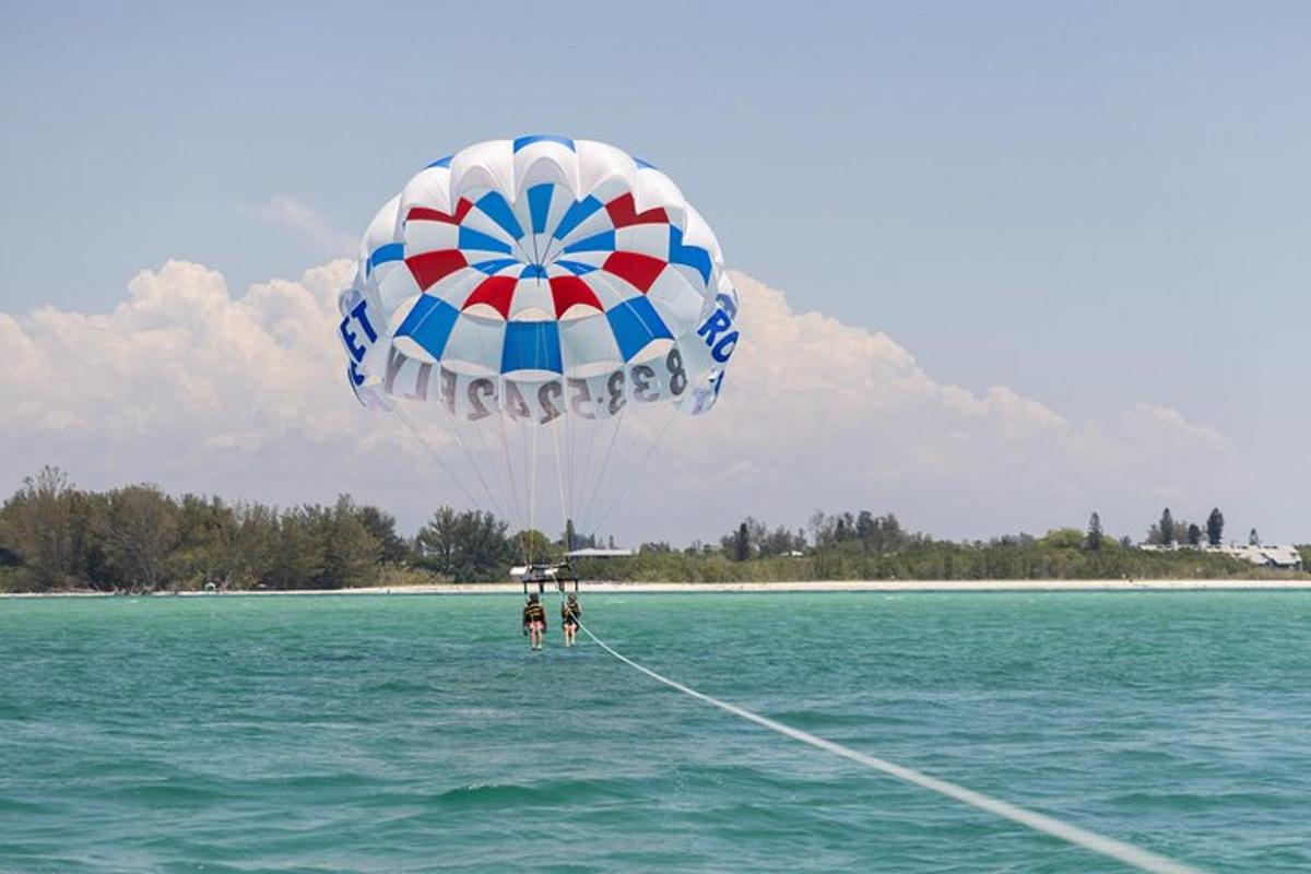a person flying a large parachute in the water