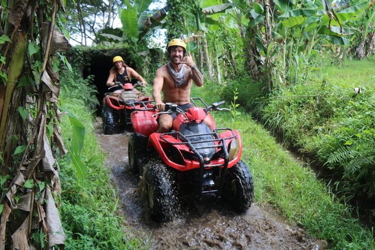 two men riding on atvs on a muddy trail