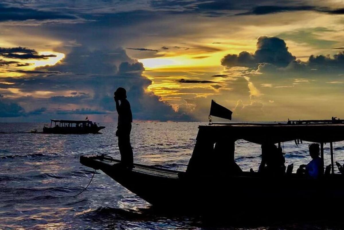 un uomo in piedi sul retro di una barca nell'oceano