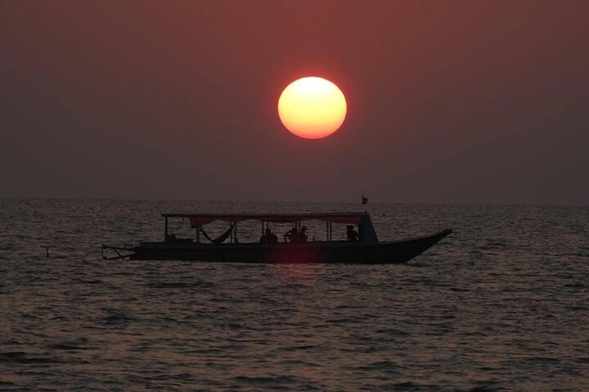 a boat in the ocean with the sun in the sky