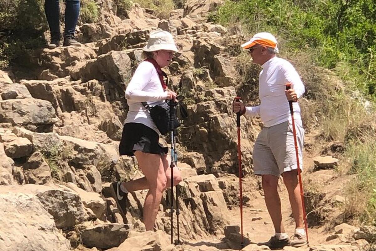 Dos personas caminando por un sendero rocoso en una montaña