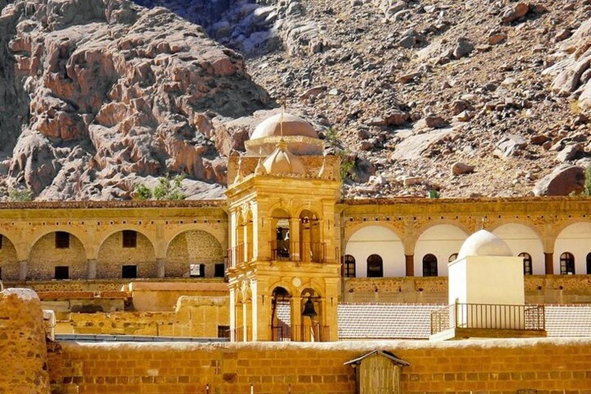 um edifício amarelo com uma torre do relógio em frente a uma montanha