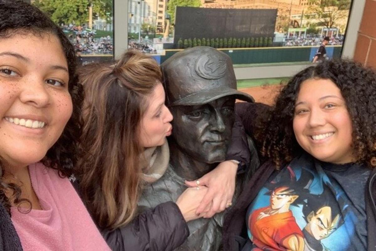 un grup de trei femei care stau lângă o statuie