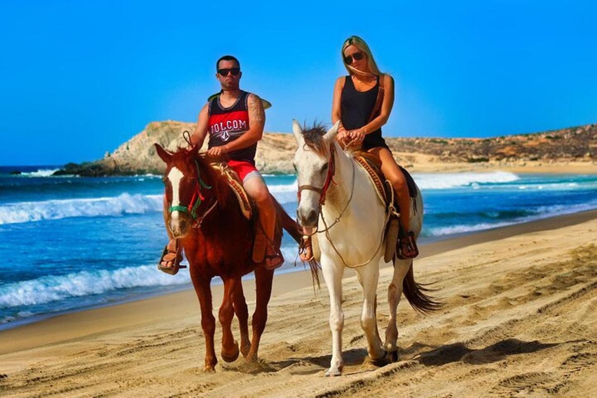 due persone a cavallo sulla spiaggia