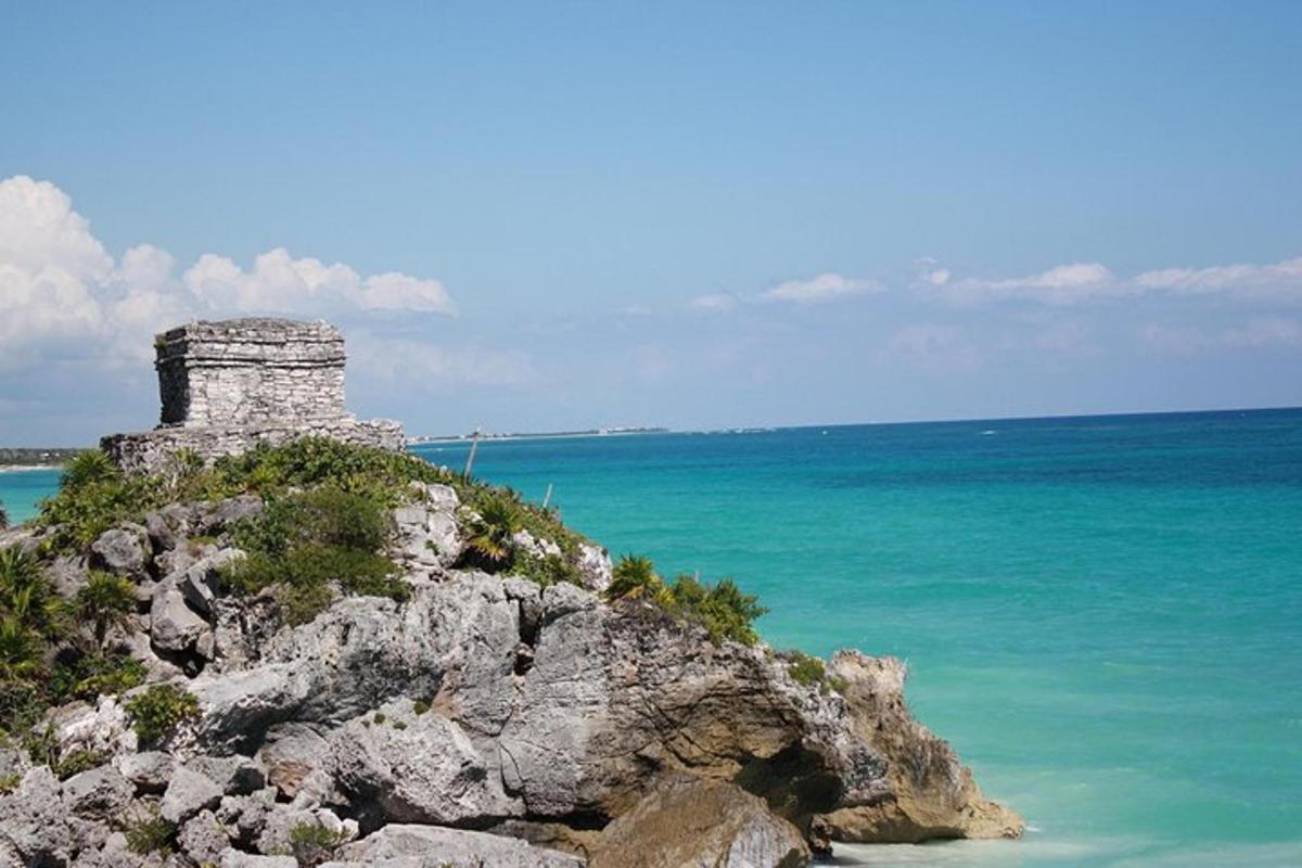 um edifício de pedra no topo de uma colina rochosa perto do oceano