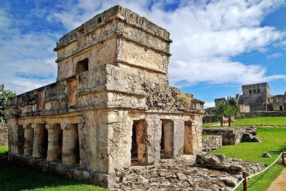 Un antiguo edificio de piedra en un campo con un castillo al fondo.