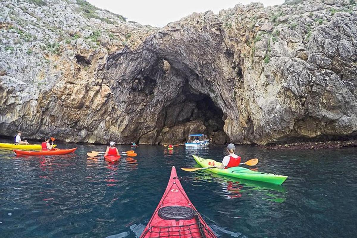 a group of people kayaking in the water near a cave