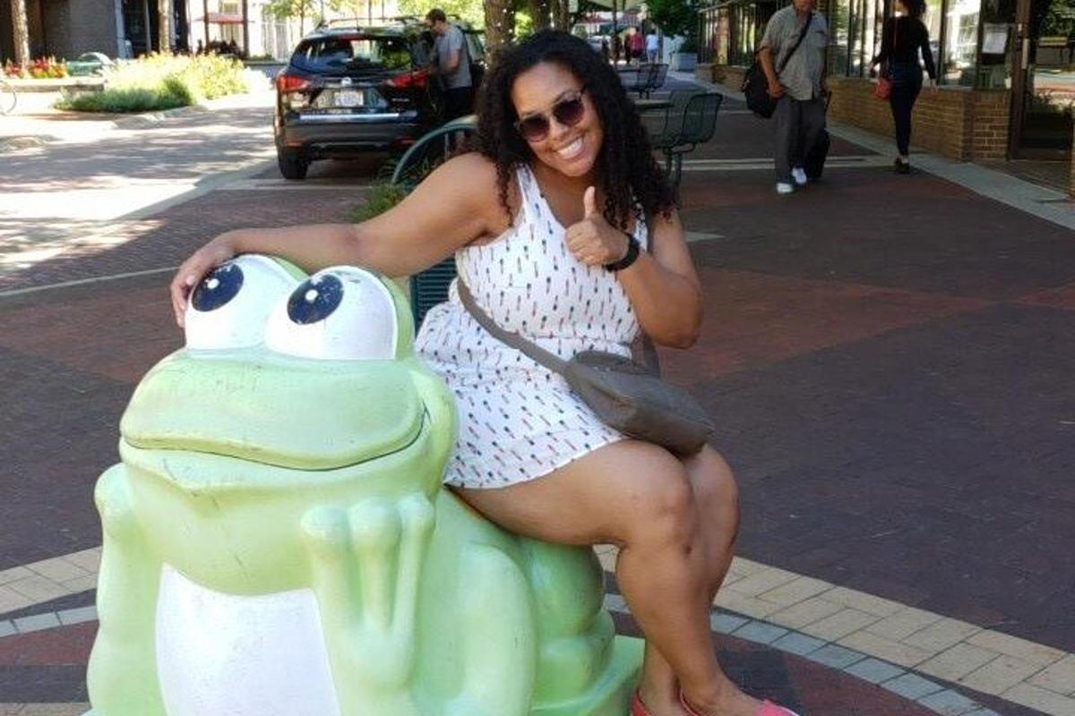 una donna è seduta su una statua di rana