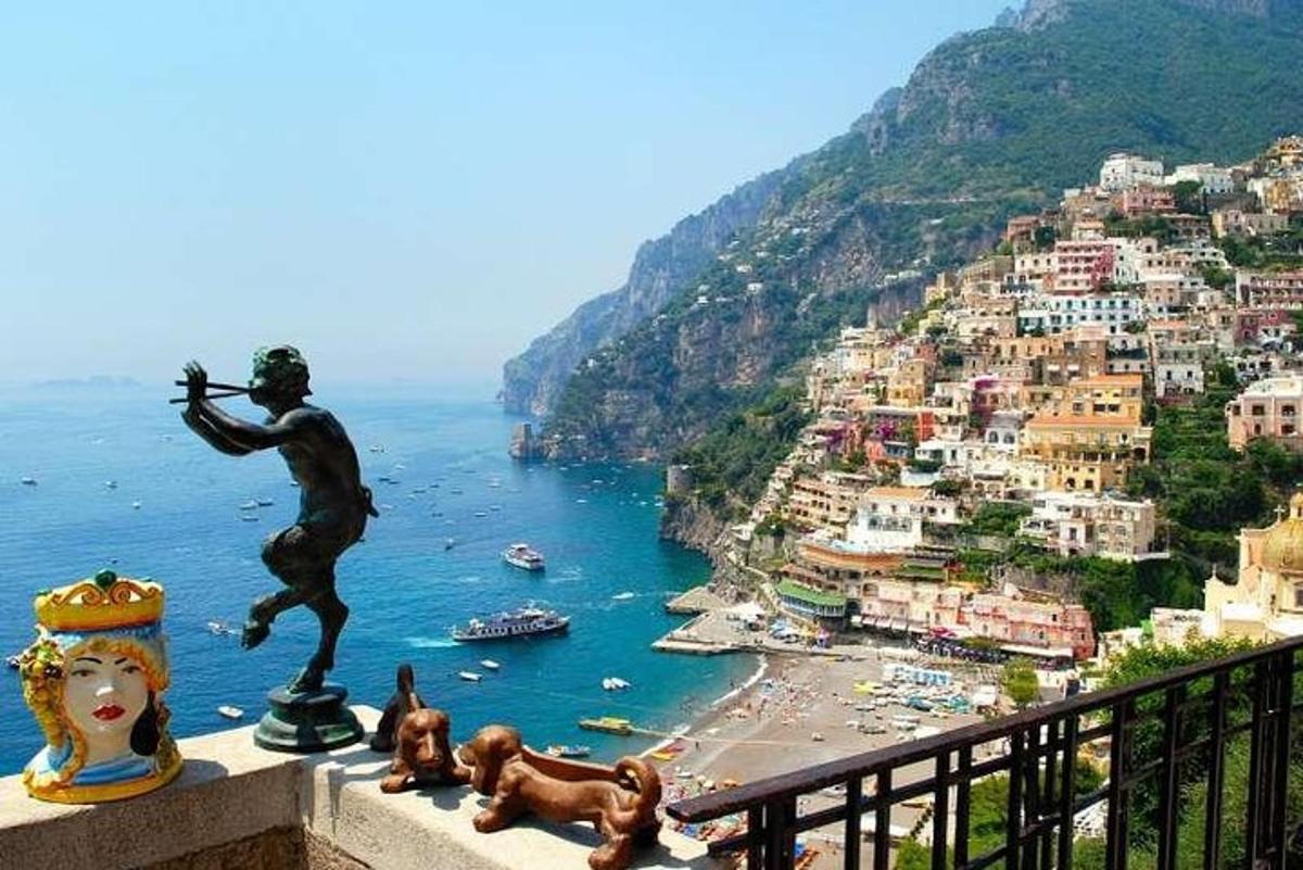 una statua di un ragazzo su una sporgenza che domina una città