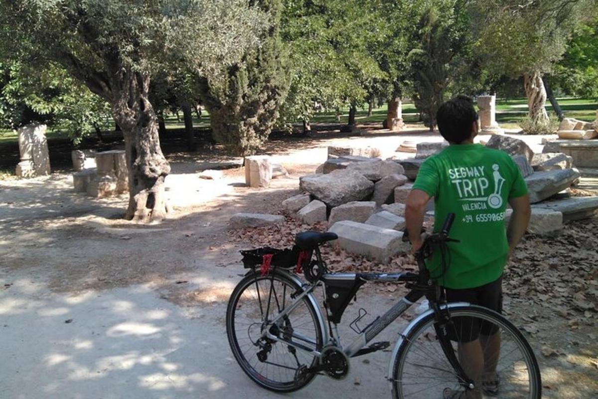 a man standing next to a bike in a park