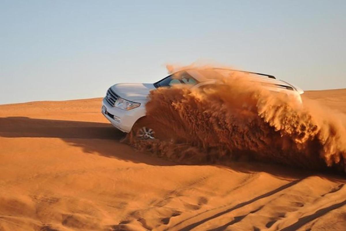 un'auto che guida attraverso la sabbia nel deserto
