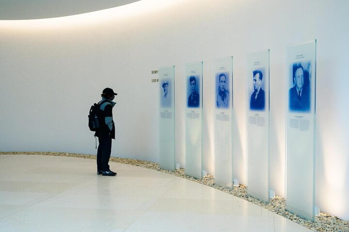a man standing in a hallway looking at pictures of faces on a wall