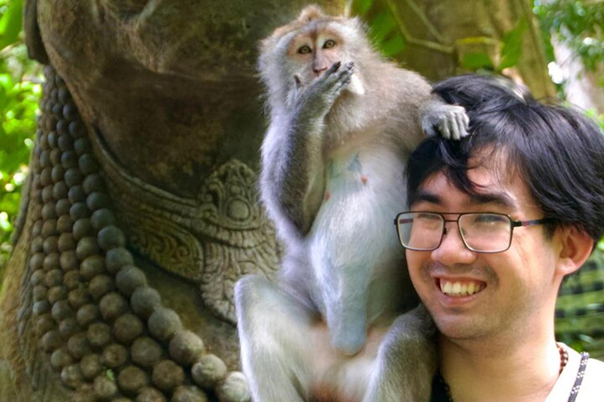 un uomo con gli occhiali che tiene una scimmia in testa