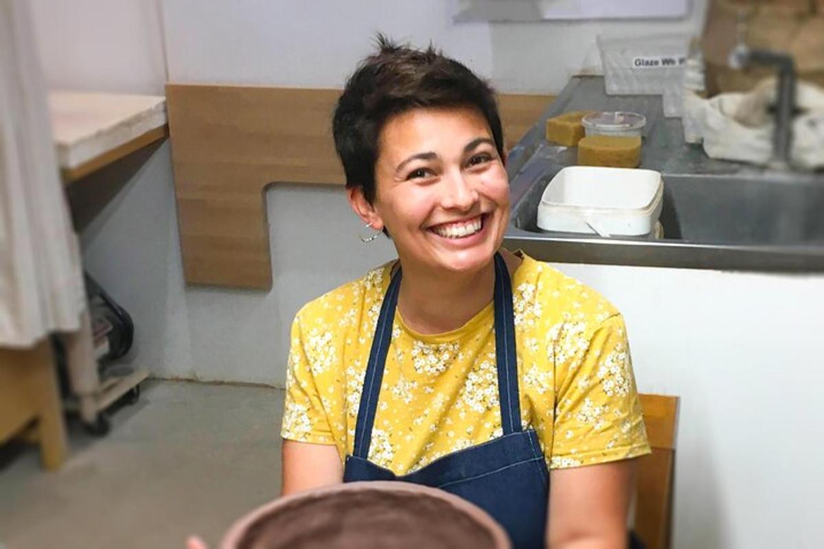 seorang wanita duduk di dapur tersenyum ke arah kamera