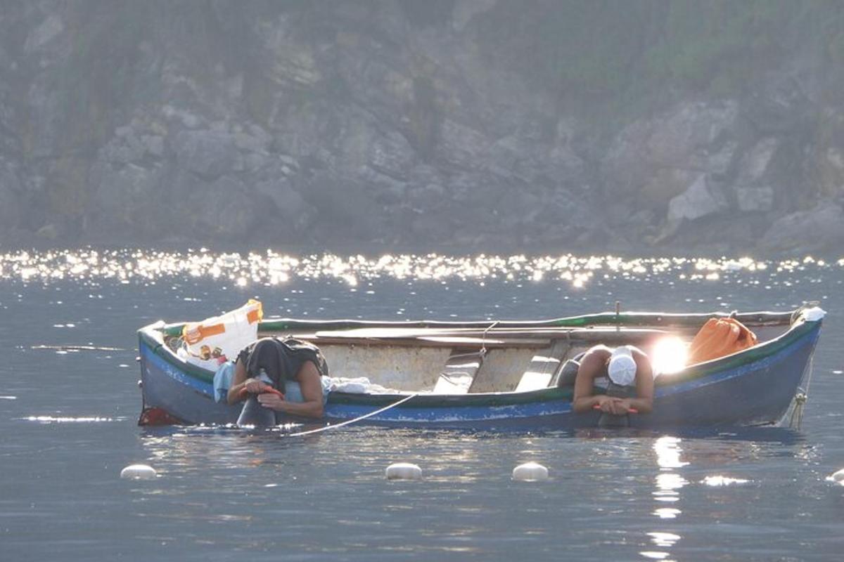 zwei Personen im Wasser neben einem Boot im Wasser