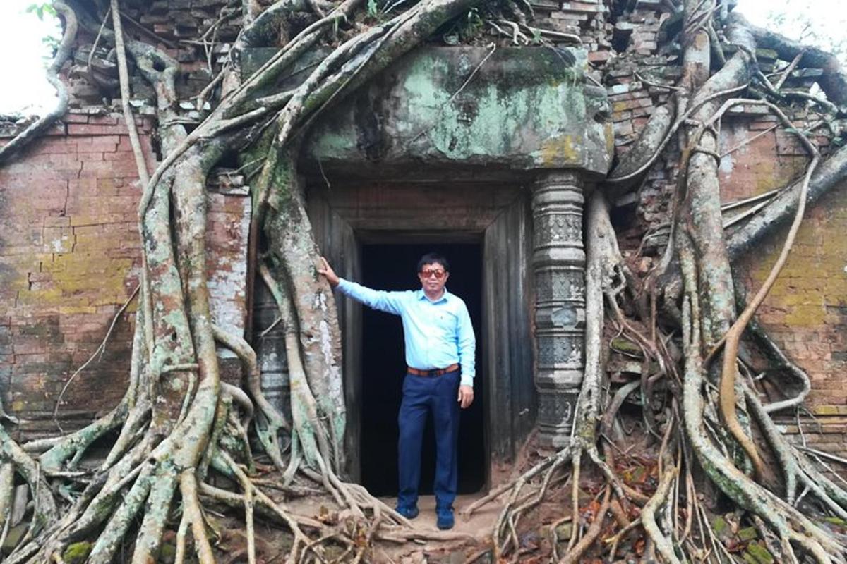 um homem parado em uma porta com raízes de árvores