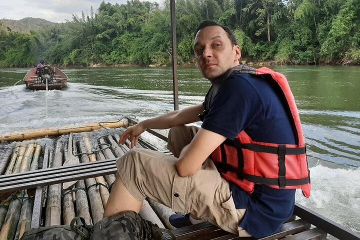 seorang lelaki dalam jaket keselamatan duduk di atas rakit di sungai