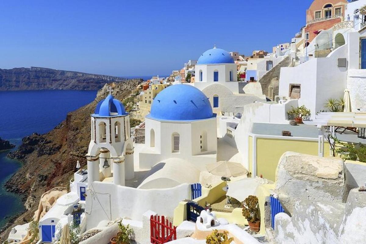 a group of white buildings with blue domes on a cliff
