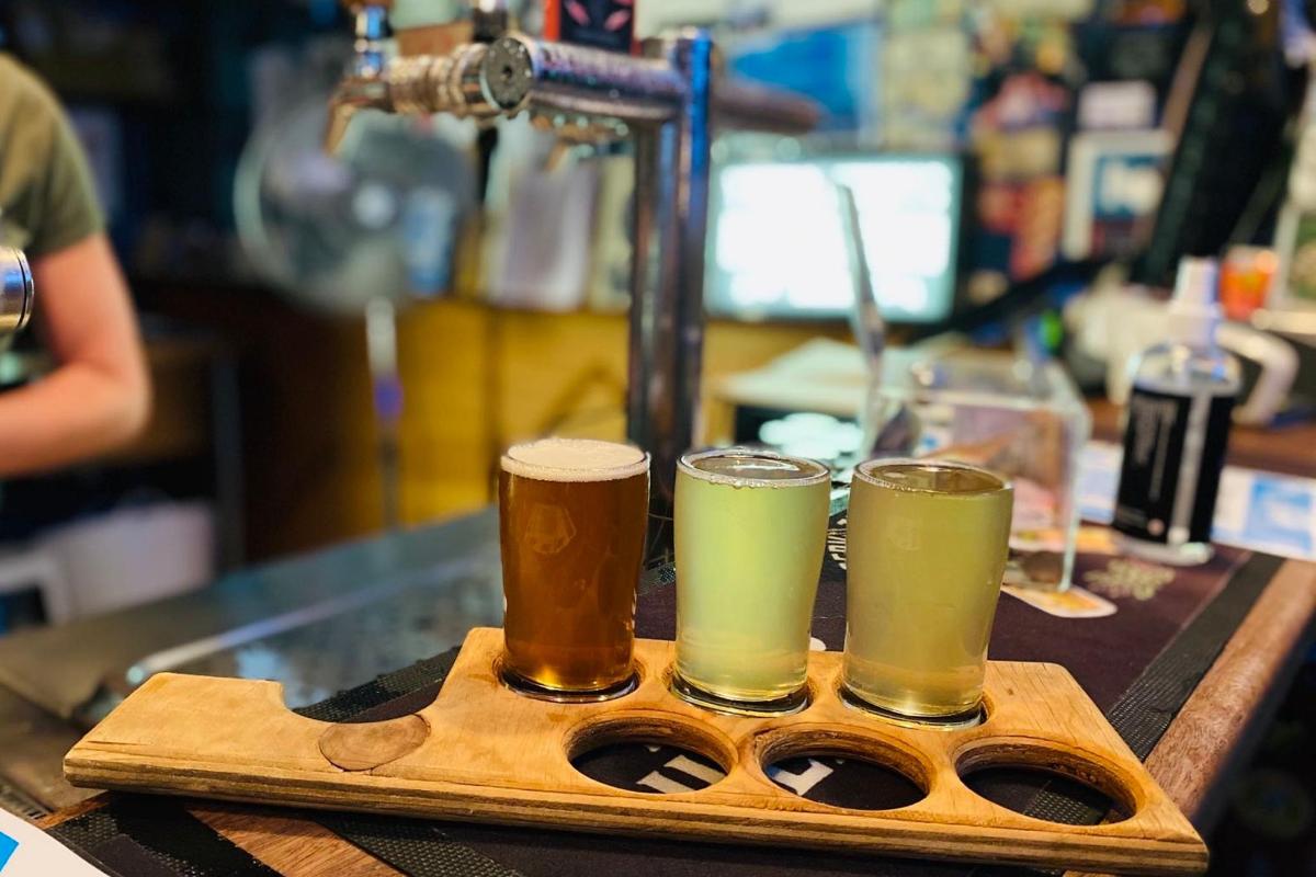 three glasses of beer sitting on a wooden tray