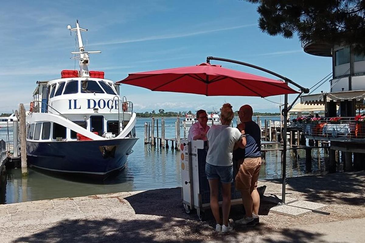 a group of people standing under an umbrella near a boat