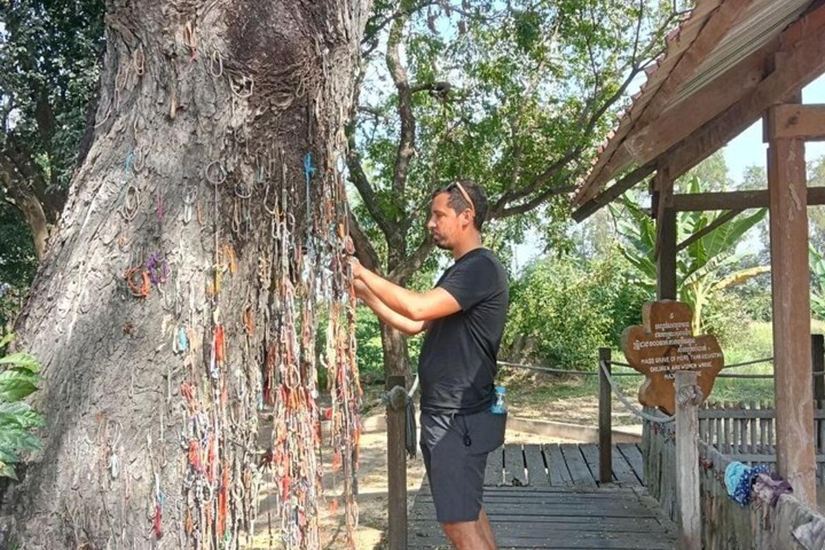 un home dret al costat d'un arbre amb un munt de cadenes