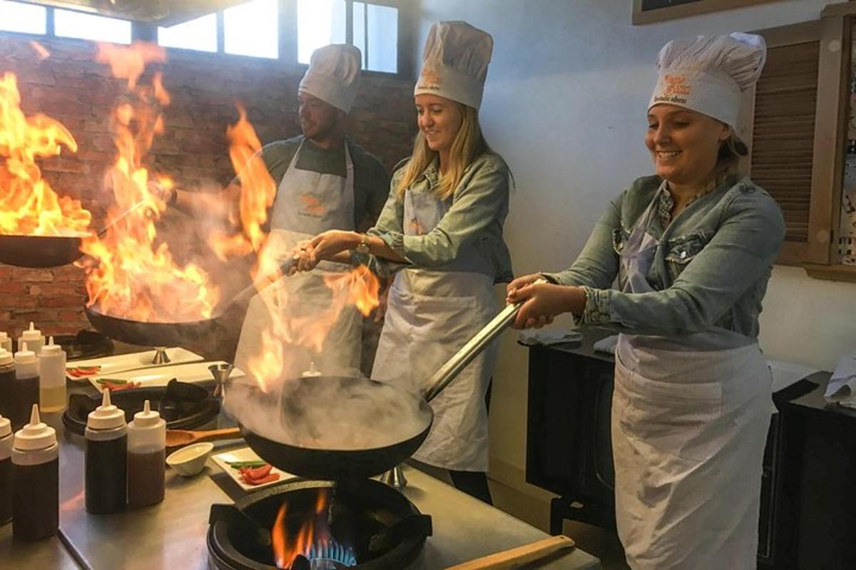 Dos mujeres y un hombre en una cocina cocinando en una parrilla