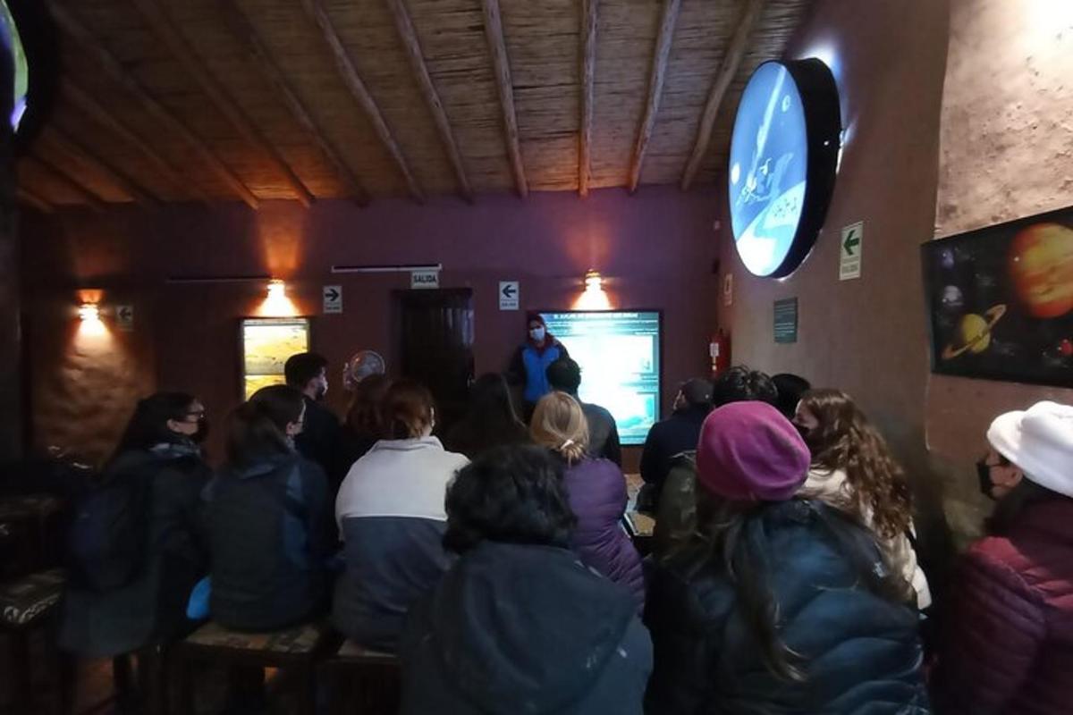 un grup de persones en una habitació amb un home en una pantalla