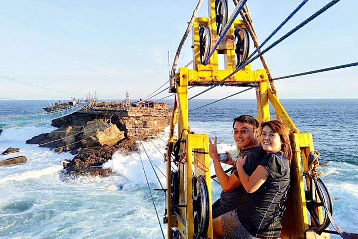 un uomo e una donna seduti su una gru gialla nell'oceano