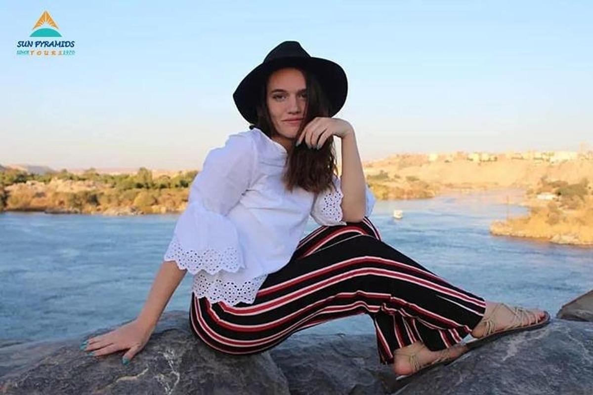 امرأة ترتدي قبعة وتجلس على صخرة