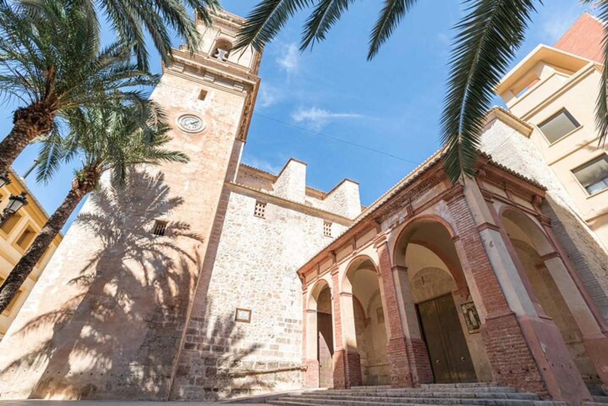 una chiesa con una torre dell'orologio e palme