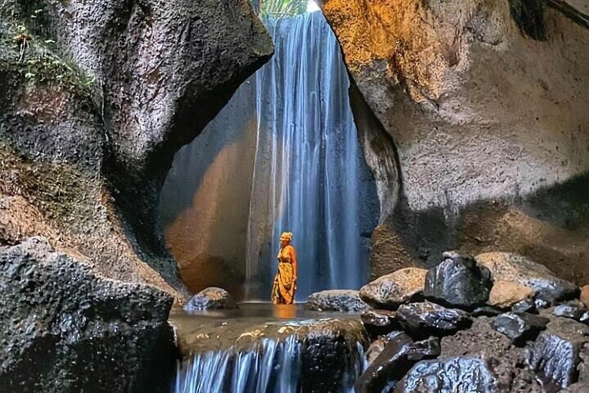 patung orang berdiri di hadapan air terjun