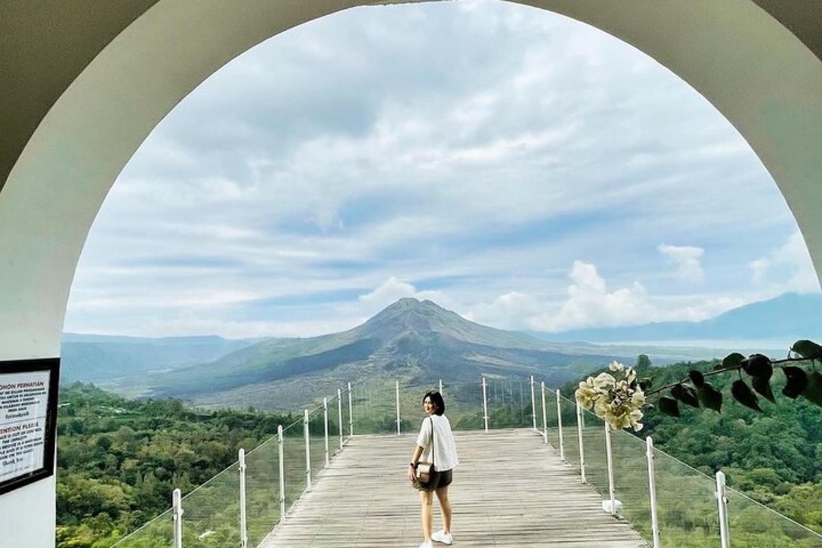 a woman standing on a bridge looking at a mountain