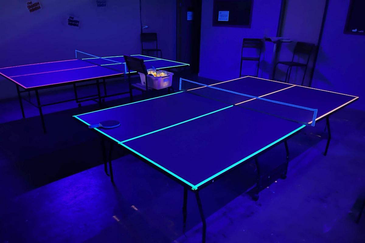 dua meja ping pong dalam bilik dengan lampu biru