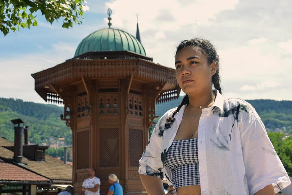 Una mujer parada frente a un edificio con una torre.