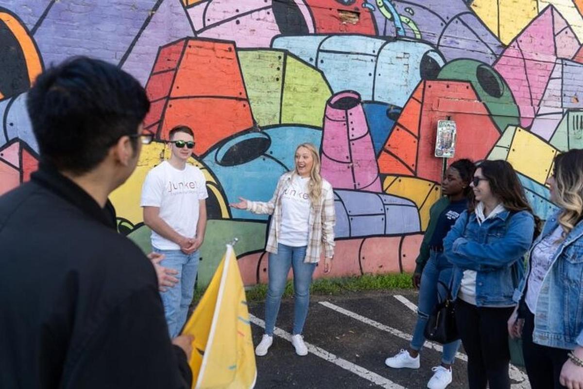un gruppo di persone in piedi davanti a un murale