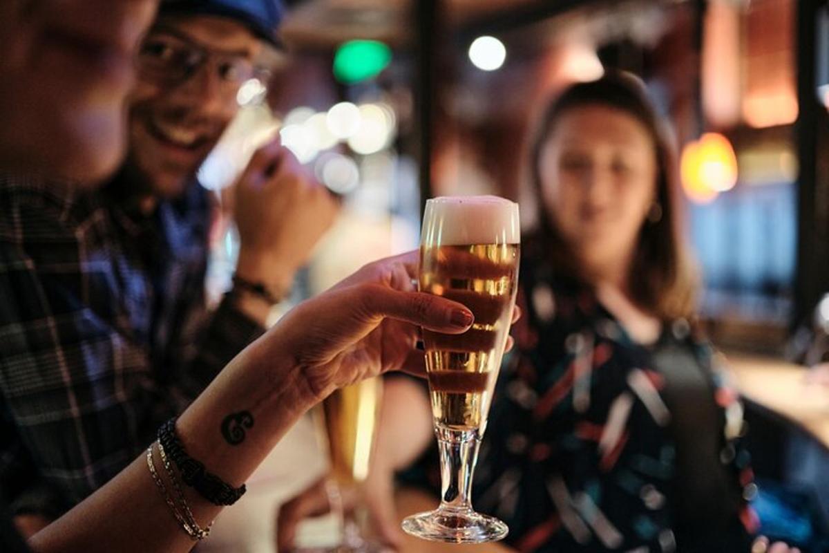 una persona che tiene in mano un bicchiere di birra in un bar