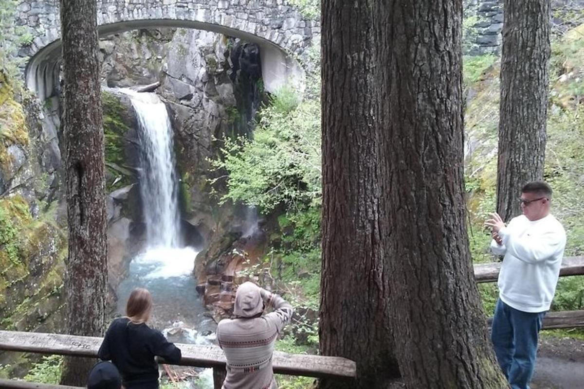 μια ομάδα ανθρώπων που στέκονται μπροστά σε έναν καταρράκτη