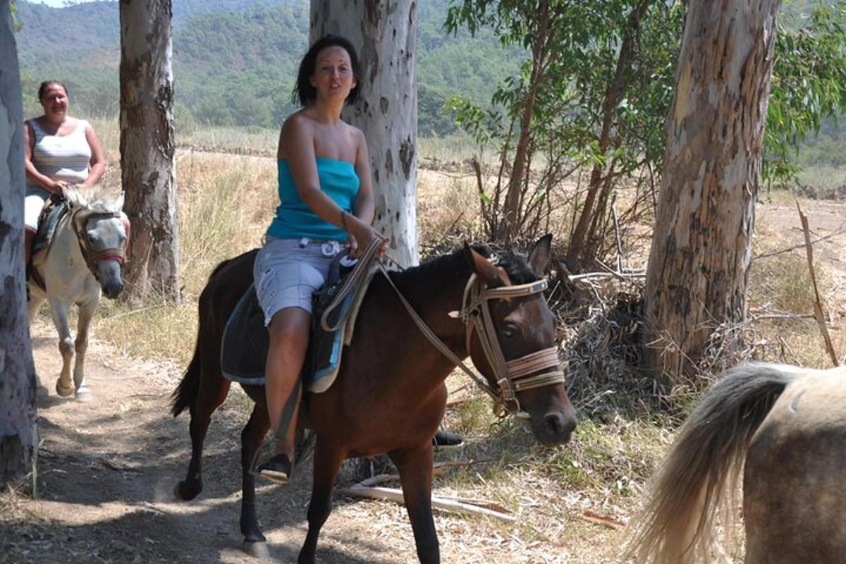 o femeie călare pe un cal în pădure