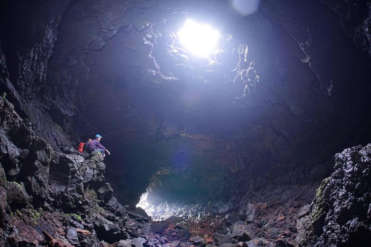 uma pessoa parada em uma caverna com uma luz no topo