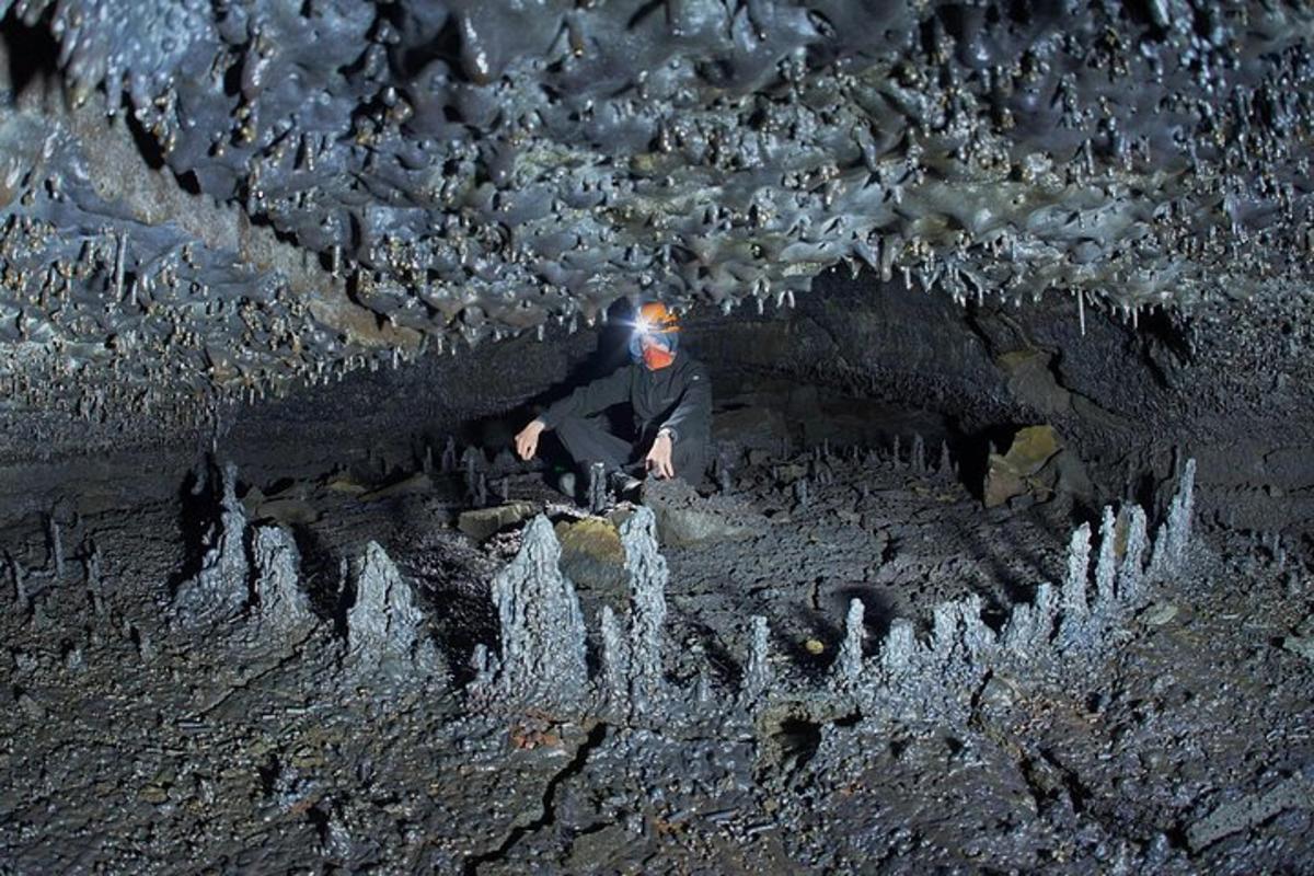 Un hombre está parado en una cueva con rocas.