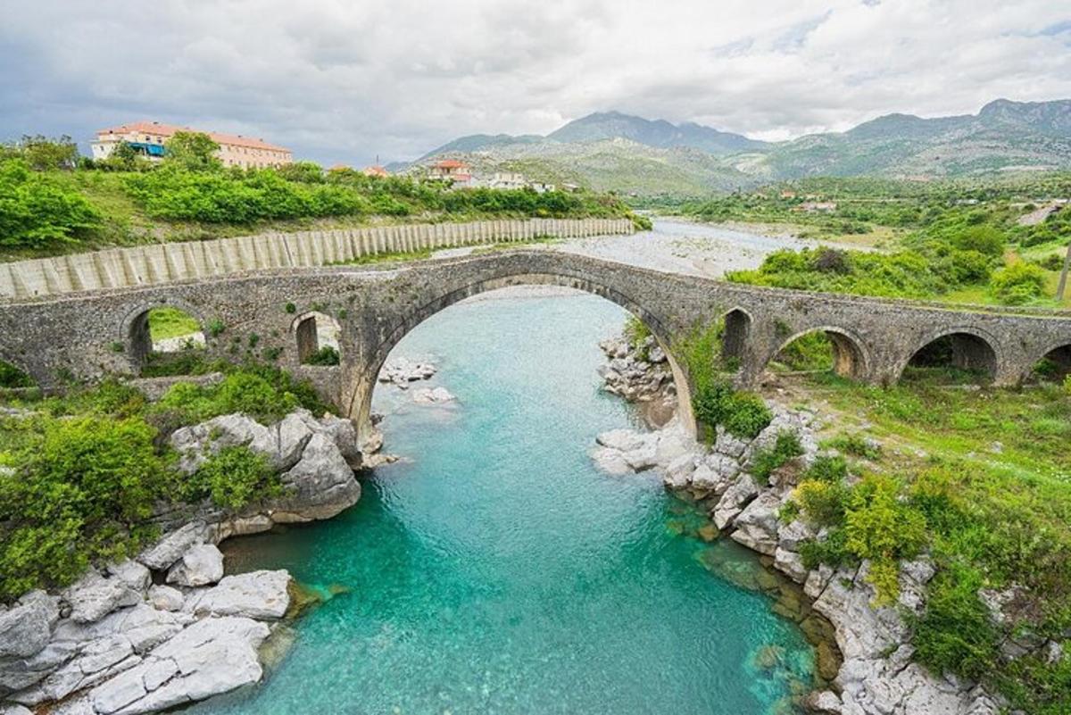 un vechi pod de piatră peste un râu cu apă albastră