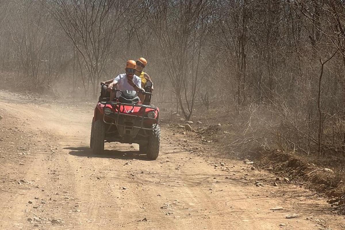 two people riding in a four wheeler on a dirt road