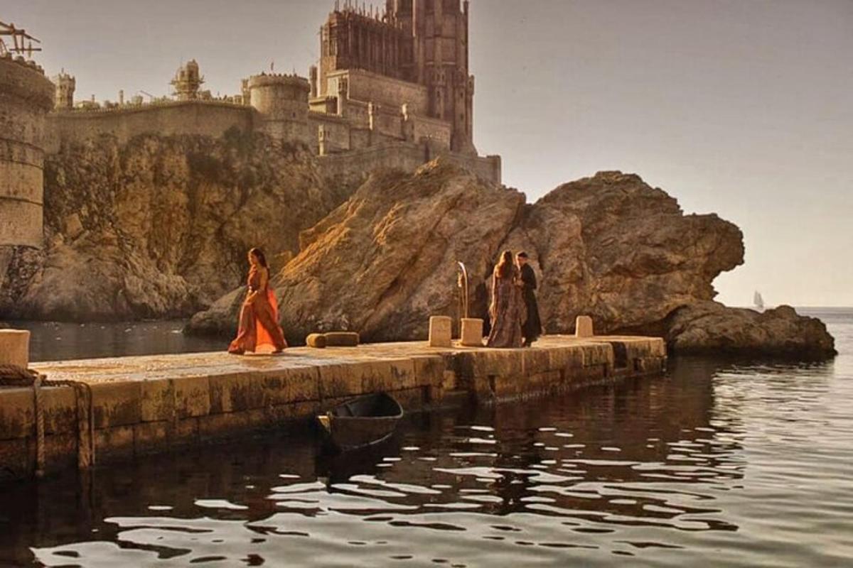 Þrjár konur ganga á bryggju fyrir framan kastala