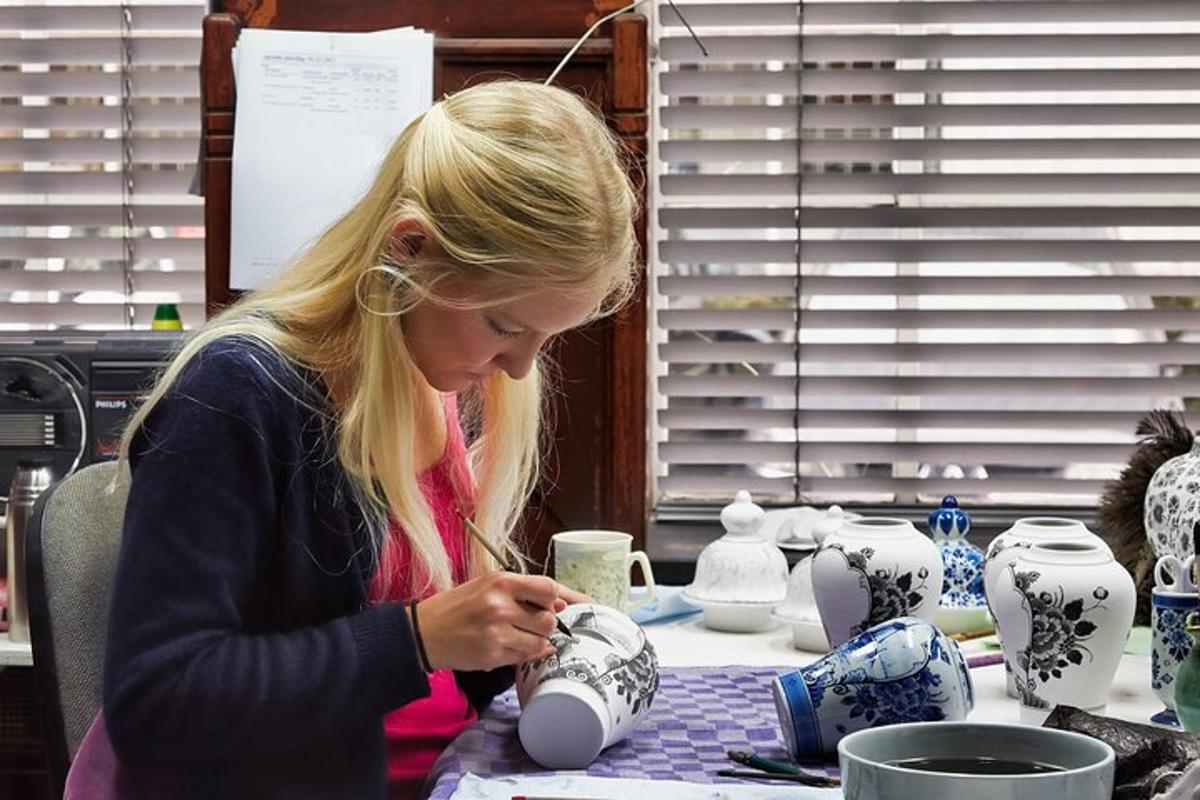 een vrouw die aan een tafel zit en aan een vaas werkt