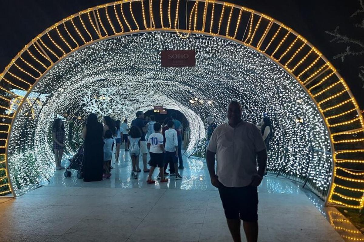 sekumpulan orang berjalan melalui terowong dengan lampu krismas