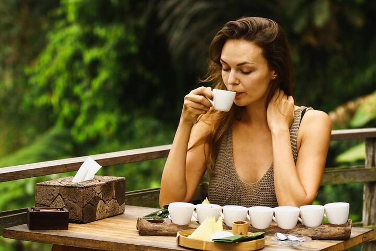 a woman sitting at a table drinking a cup of coffee