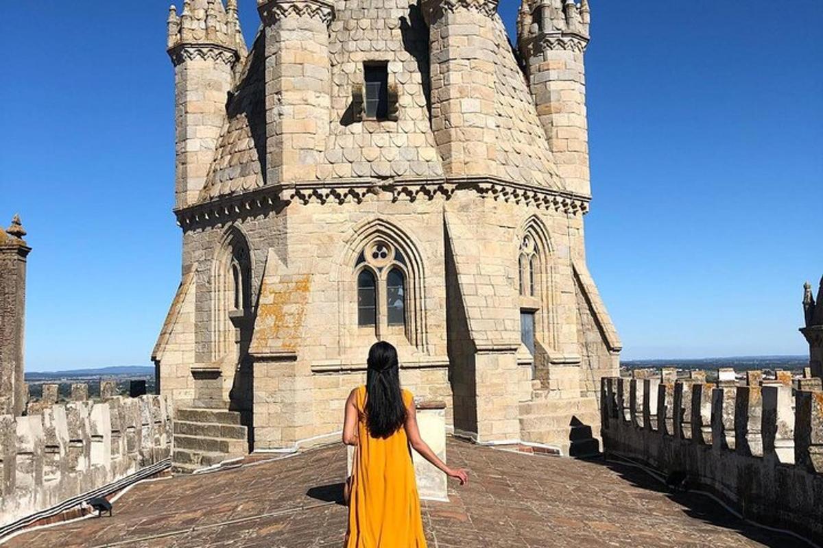 Una mujer con un vestido amarillo parada frente a un castillo.